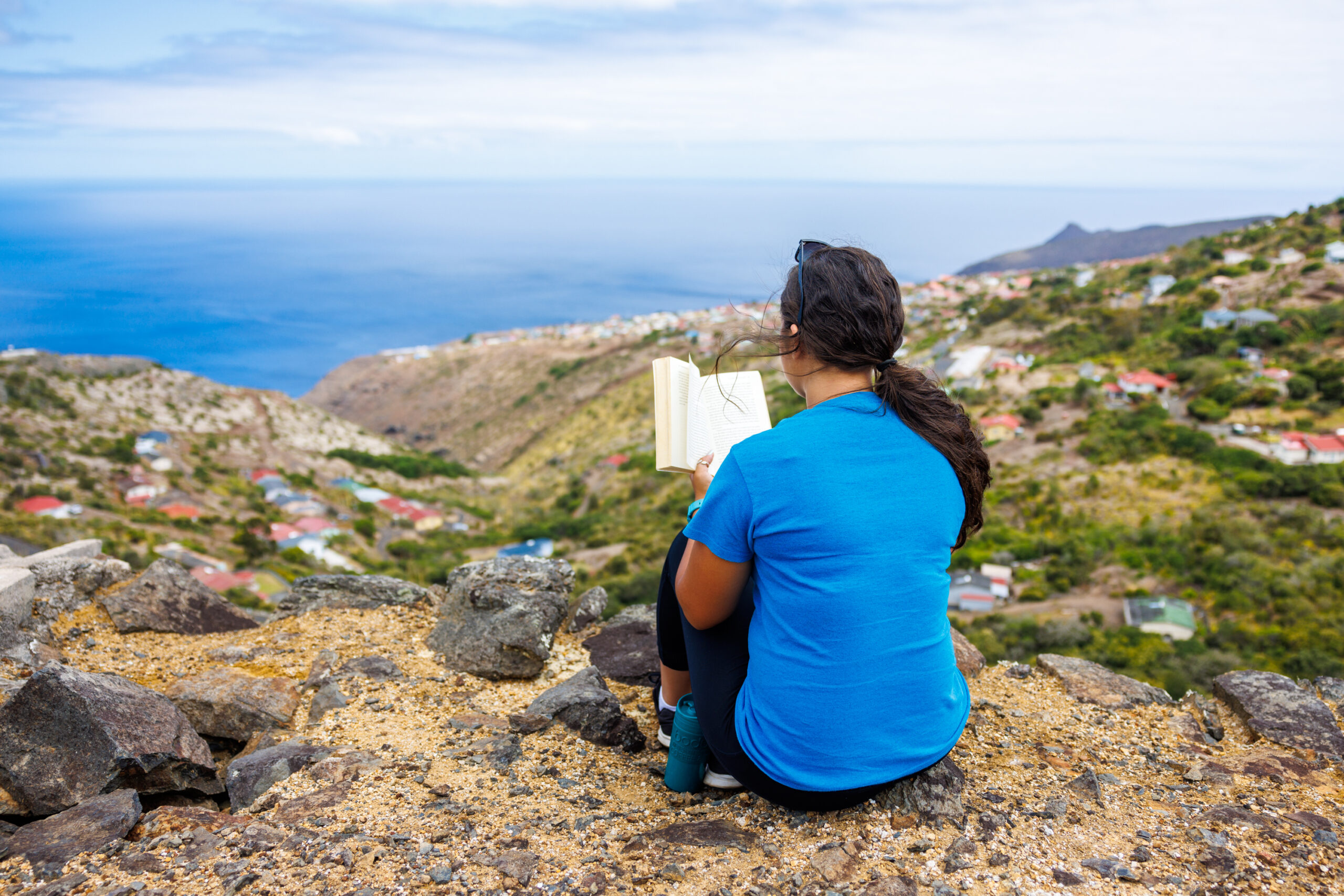 Woman Reading Book on top of mountain